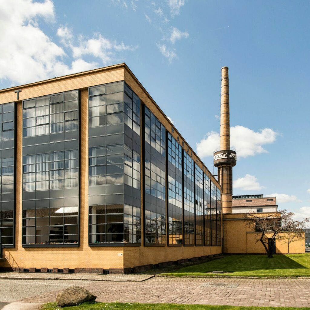 Modernist factory building with large windows and chimney.